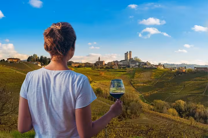 Tourist enjoying Chianti wine while overlooking the rolling hills of San Gimignano on a Tuscany wine tour.
