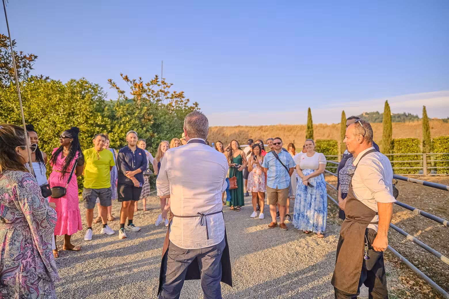 Small-group tour participants listening to a winery guide in Chianti, surrounded by beautiful vineyard landscapes.