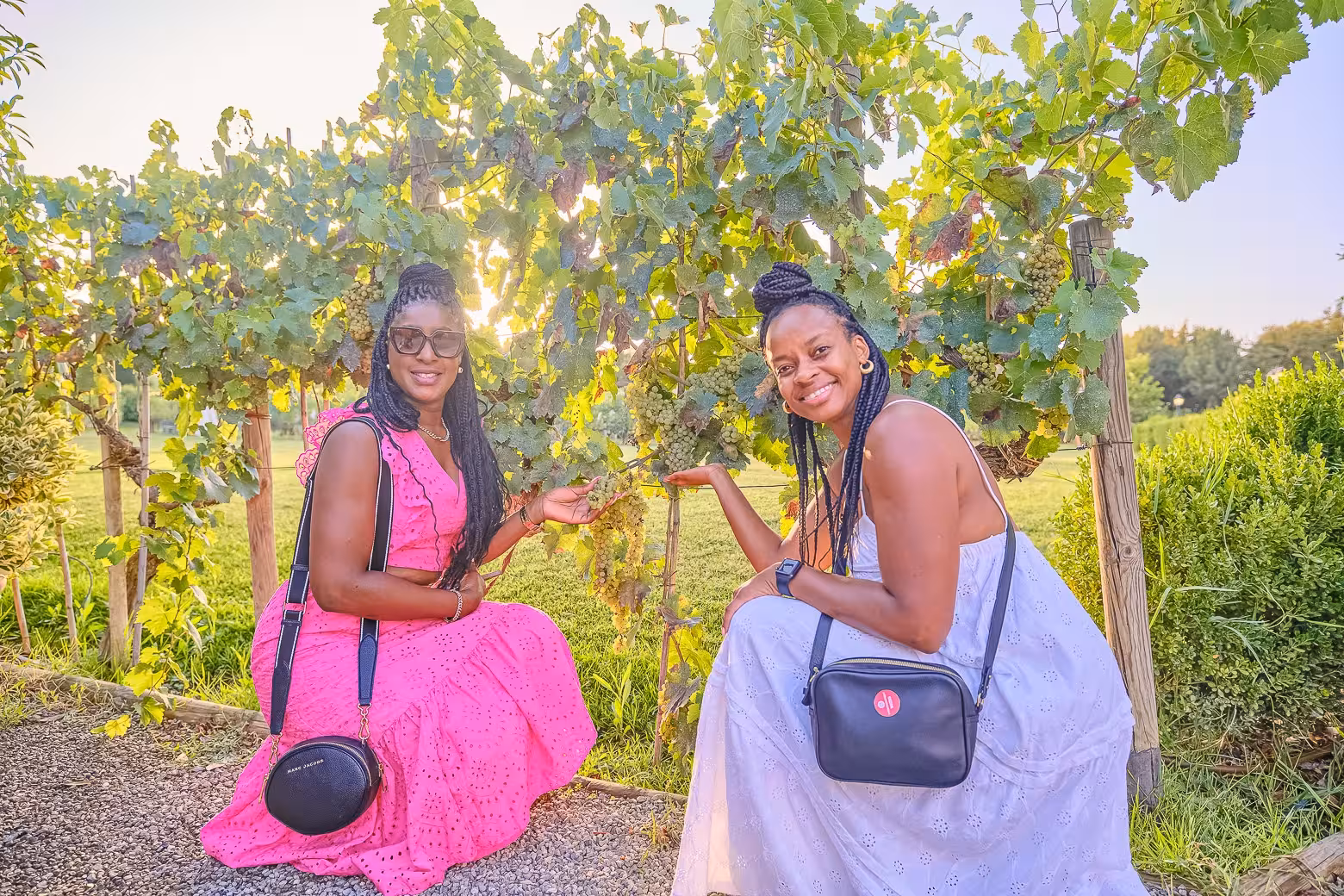 Two women smiling beside lush grapevines during a Chianti vineyard tour, showcasing Tuscany's wine beauty.