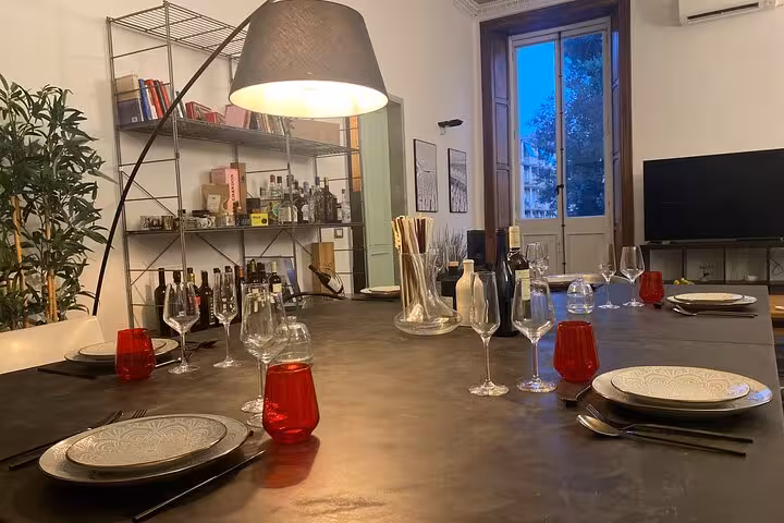 Elegant dining setup for a Chiavari food tour with wine glasses and plates, set in a cozy interior with bookshelves.