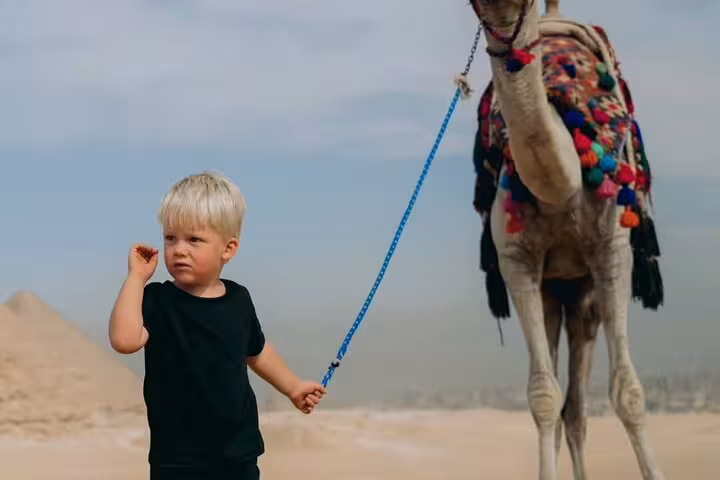 Small child holding a camel lead in the Giza desert near the pyramids, part of an ultimate 3-day Cairo tour