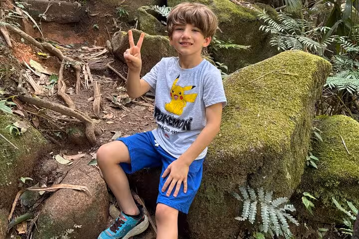 Smiling child posing on a scenic Mahe Island hiking trail surrounded by lush greenery during a private Seychelles tour.
