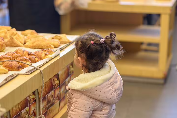 A child admires fresh pastries in a Le Marais bakery during a Paris Flavors of France private walking food tour.