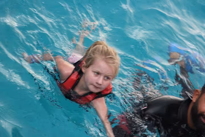 Child swimming in turquoise Red Sea with life vest on Hula Hula Island Hurghada snorkeling day trip