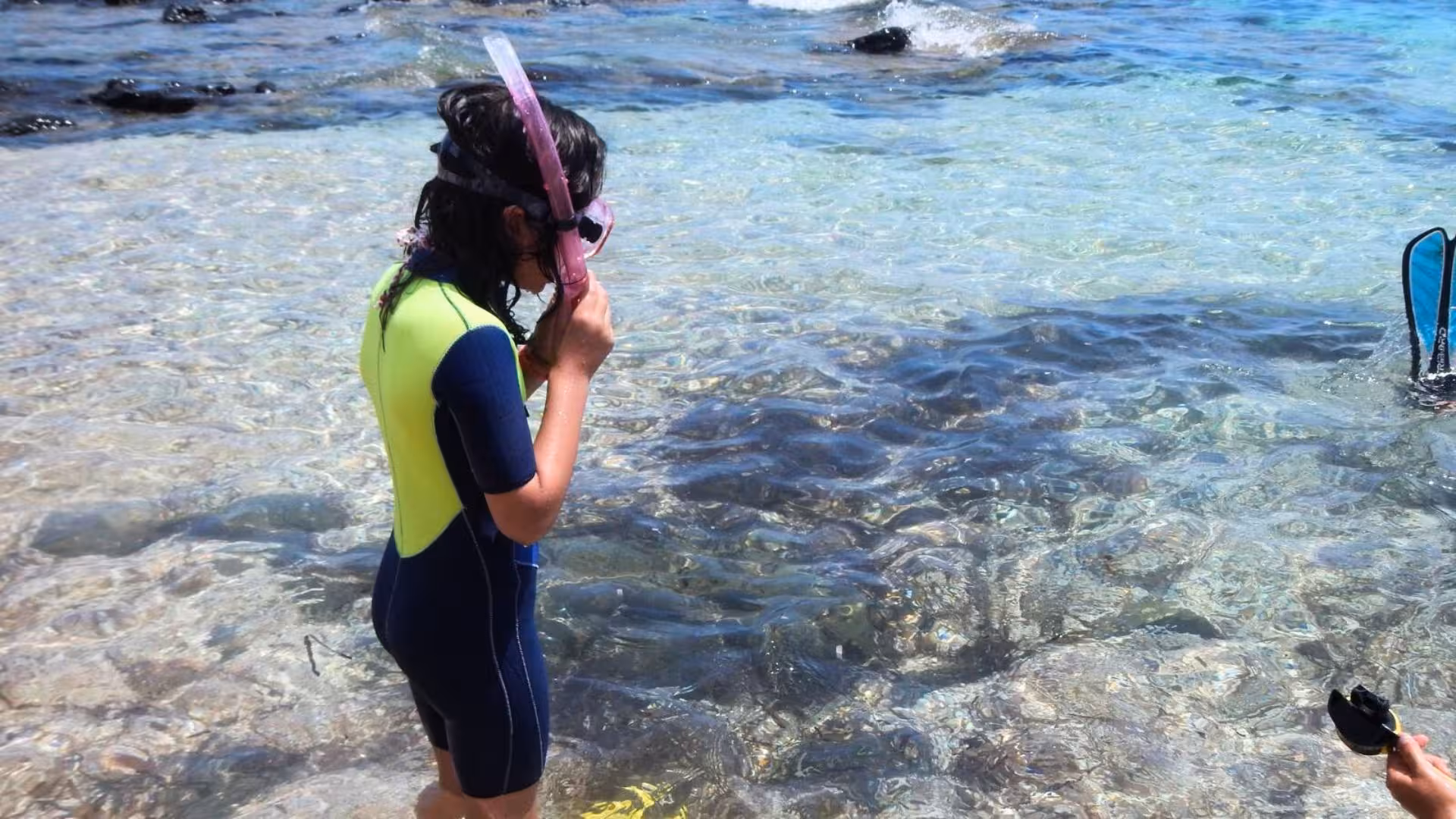Child in wetsuit and snorkel gear explores clear waters at Cala Gonone, ideal for underwater baptism experiences.