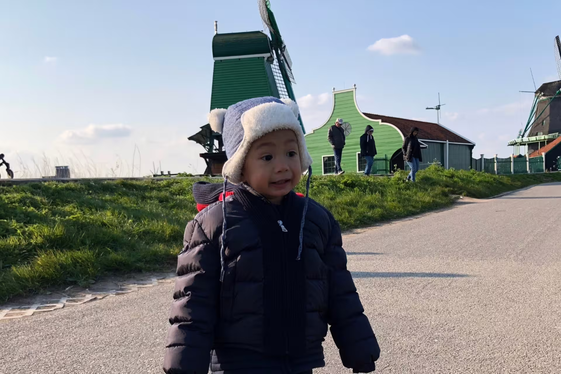 Child near Zaanse Schans green windmill on Amsterdam day tour to Giethoorn and Zaanse Schans