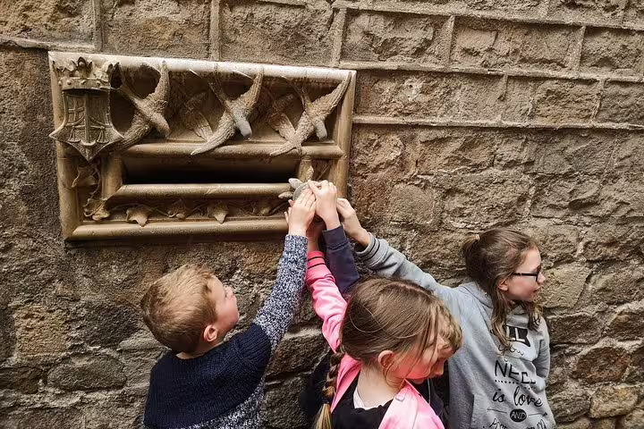 Children exploring a historic stone wall in Barcelona's Gothic Quarter on a private city highlights tour for newcomers.