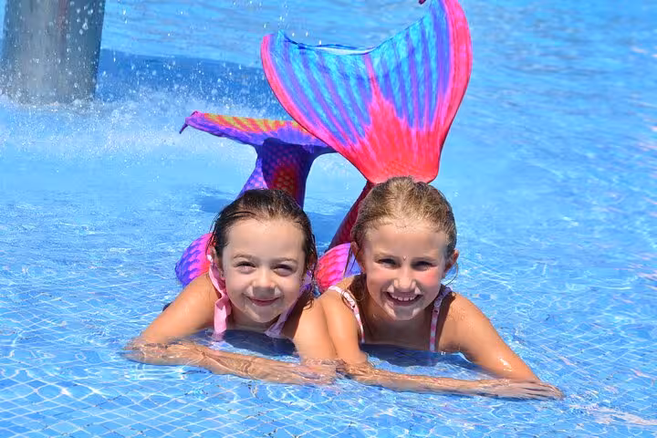 Two children enjoy a private mermaid photoshoot in Hersonissos pool, wearing colorful mermaid tails.