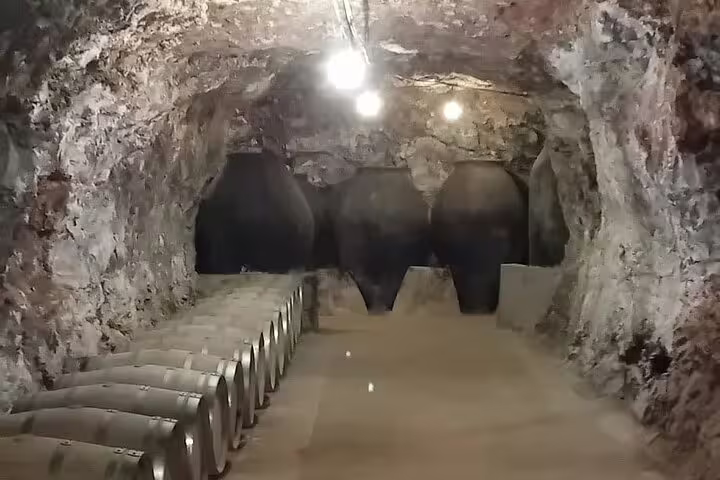 Underground wine cellar with stone walls and rows of barrels in Chinchón, offering a glimpse of Madrid's wine heritage.