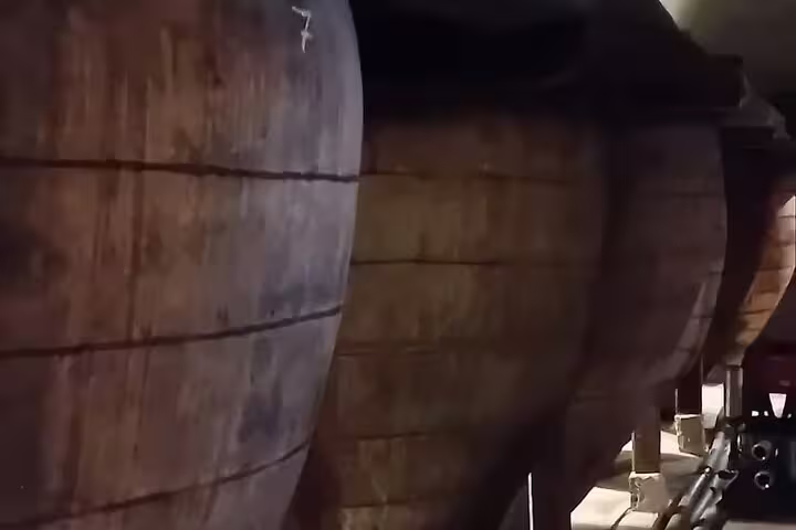 Large wooden wine barrels in a dimly lit Chinchón winery, showcasing traditional wine-aging techniques near Madrid.