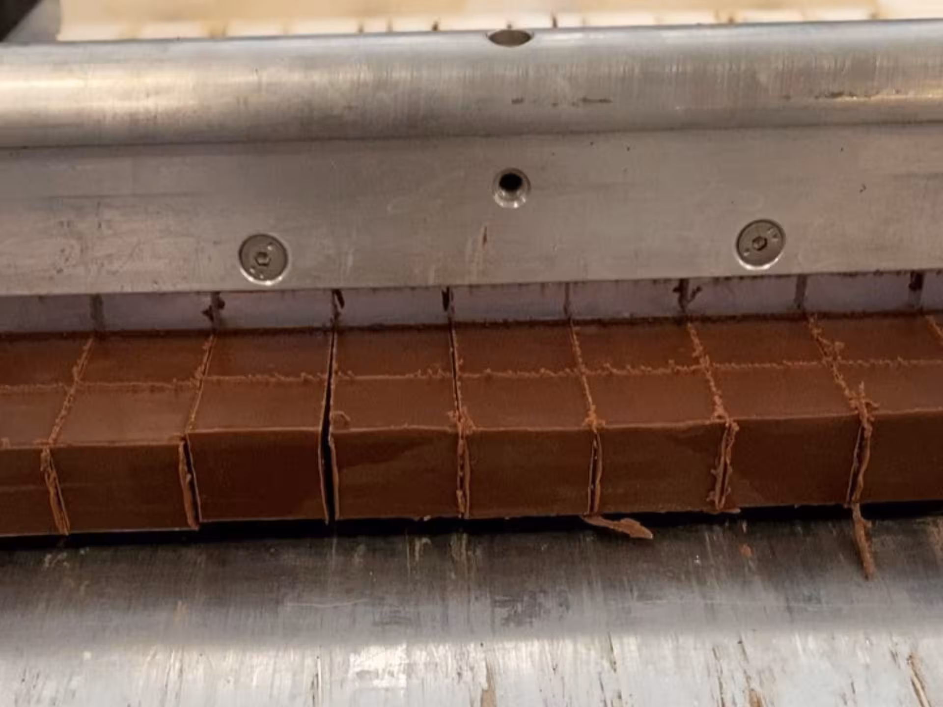 Close-up of chocolate being precisely cut into squares during a factory tour near Alessandria.