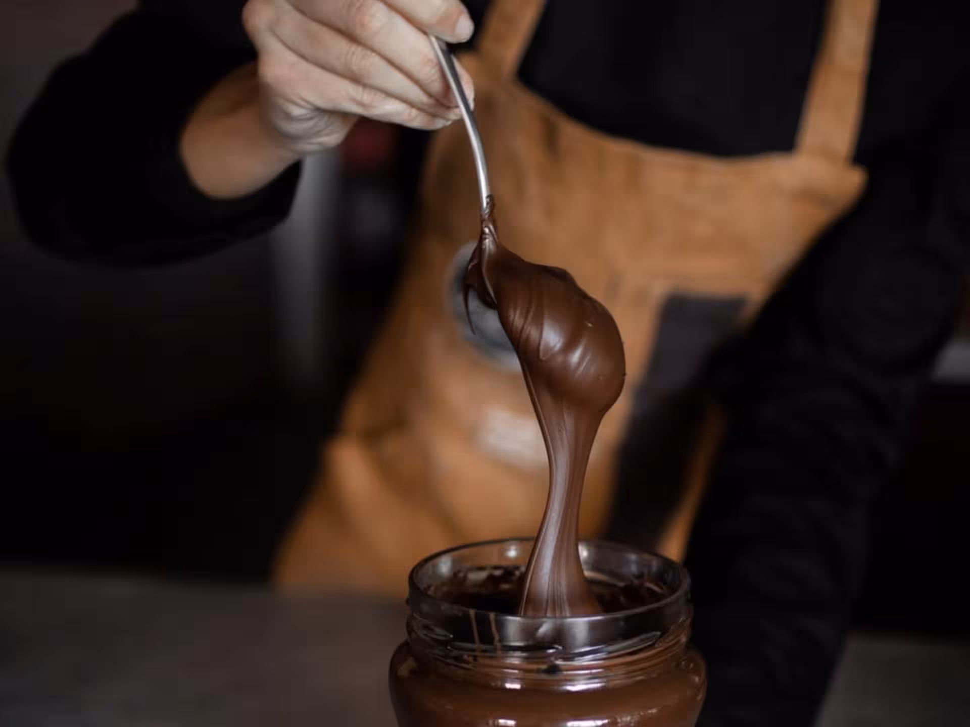 Spoon drizzling rich chocolate during Alessandria factory tour and tasting experience.