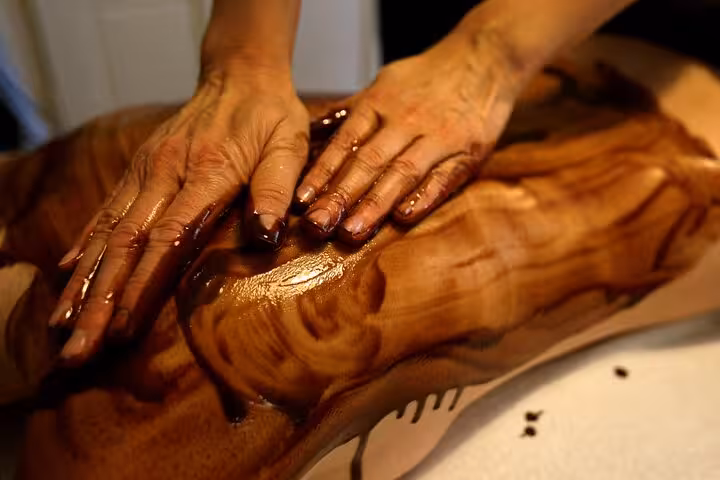 Therapist spreads melted chocolate scrub on back in Sharm El Sheikh Chocolate Magic Bath Spa Experience