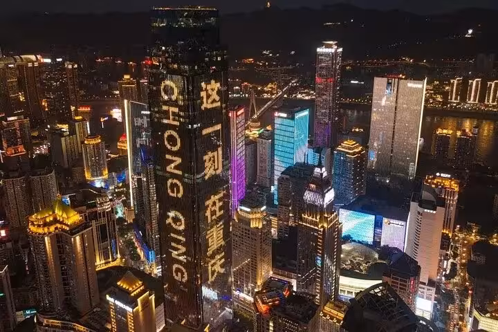 Aerial view of Chongqing's illuminated skyscrapers showcasing a vibrant cyberpunk cityscape at night.