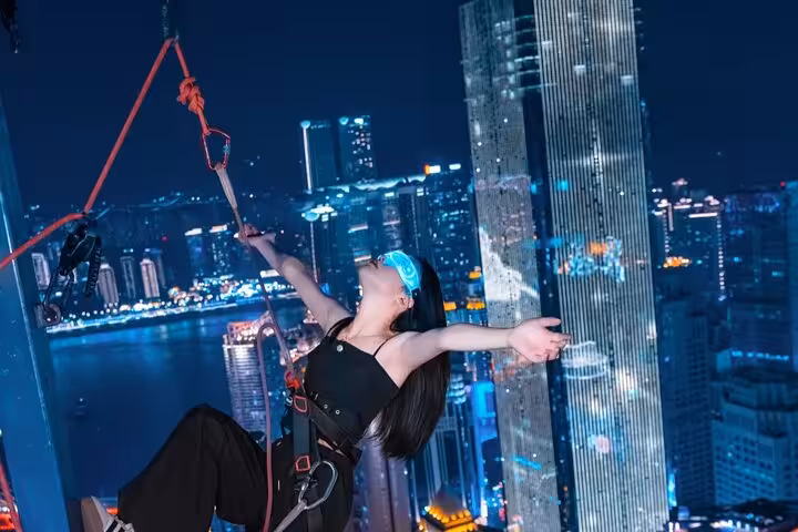 Adventurous woman suspended in the air with a harness, enjoying Chongqing's stunning city night views.
