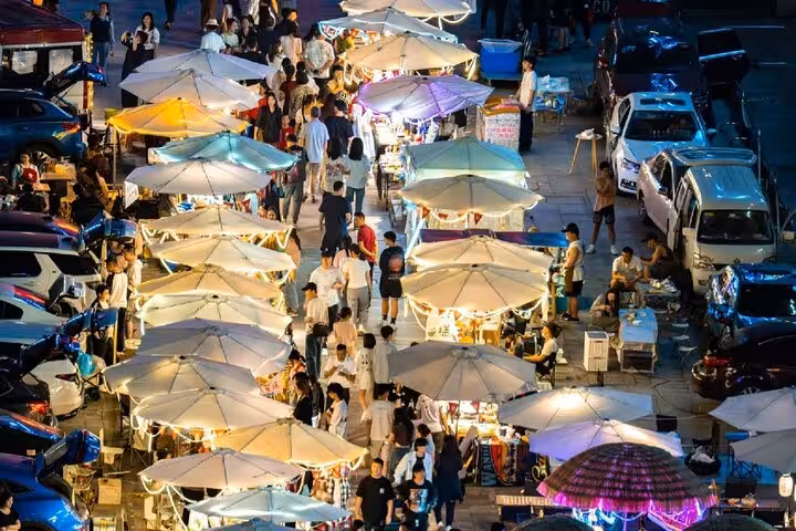 Bustling Chongqing night market with colorful umbrellas and lively crowds enjoying street food.