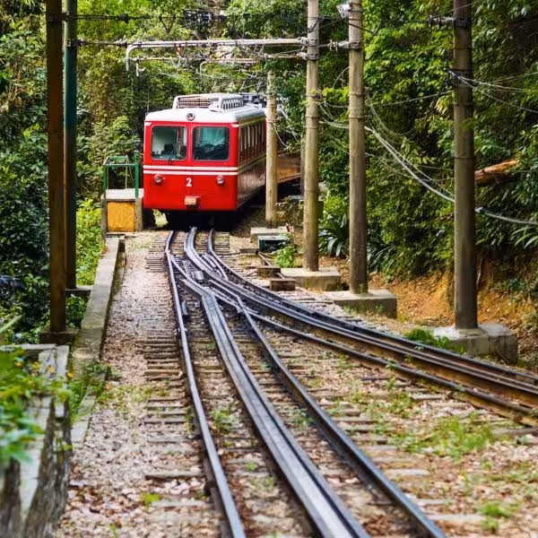Red tram ascending lush tracks to Christ the Redeemer, Rio de Janeiro tour.