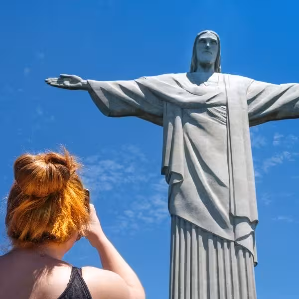 Visitor captures iconic Christ the Redeemer statue against clear blue sky in Rio.
