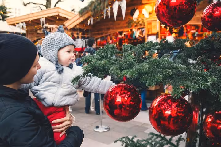 Family admiring festive Christmas market ornaments on a small-group Christmas Day trip from Vienna to Hallstatt