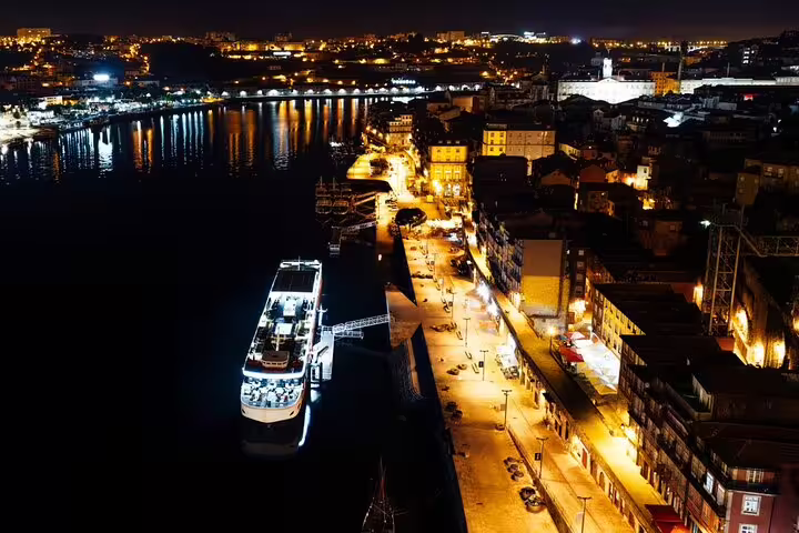 Night view of illuminated river cruise ship docked by a vibrant cityscape, showcasing the Christmas cruise experience.