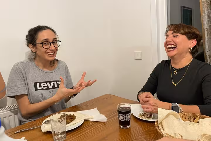Guests laugh over homemade çiğ köfte at a local home cooking class with traditional Turkish music night