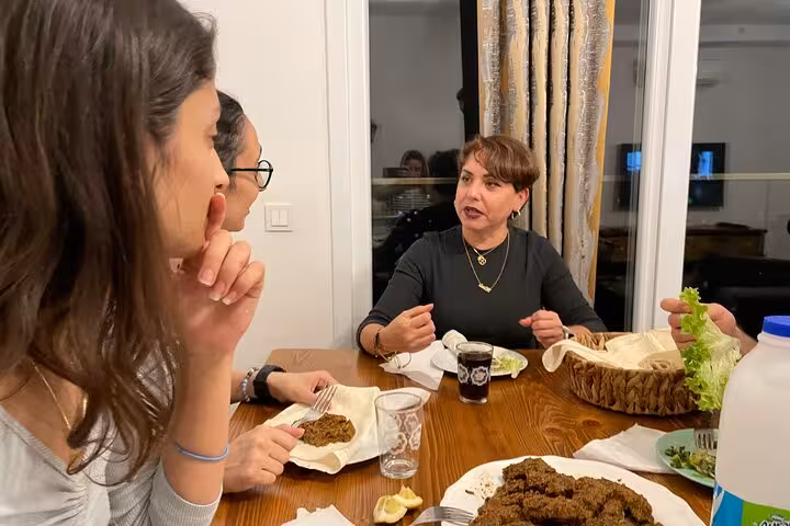 Host explains çiğ köfte at a home cooking class dinner with traditional Turkish music and shared meze table