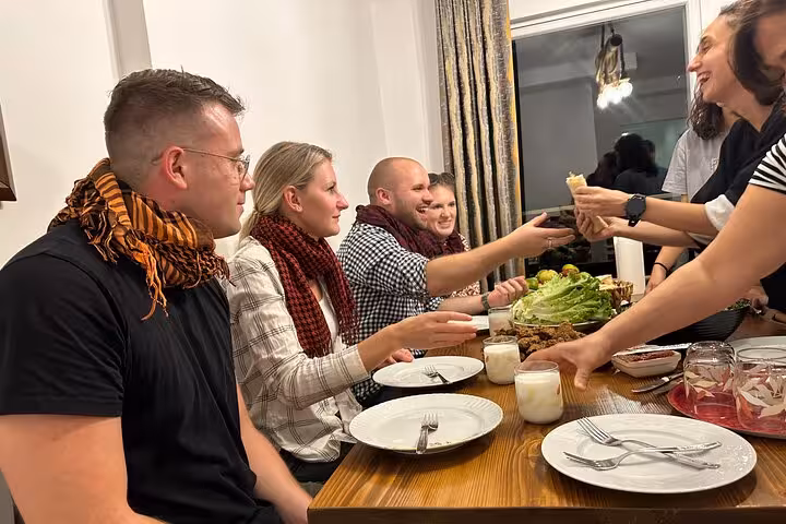 Travelers share homemade çiğ köfte and mezze at a Turkish home dinner, part of traditional music night experience
