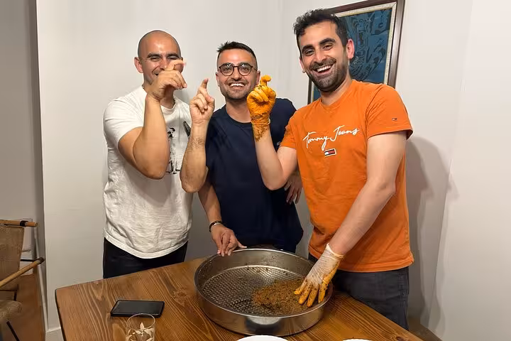 Participants shape spicy çiğ köfte mix in a home cooking class, enjoying an authentic Turkish music night