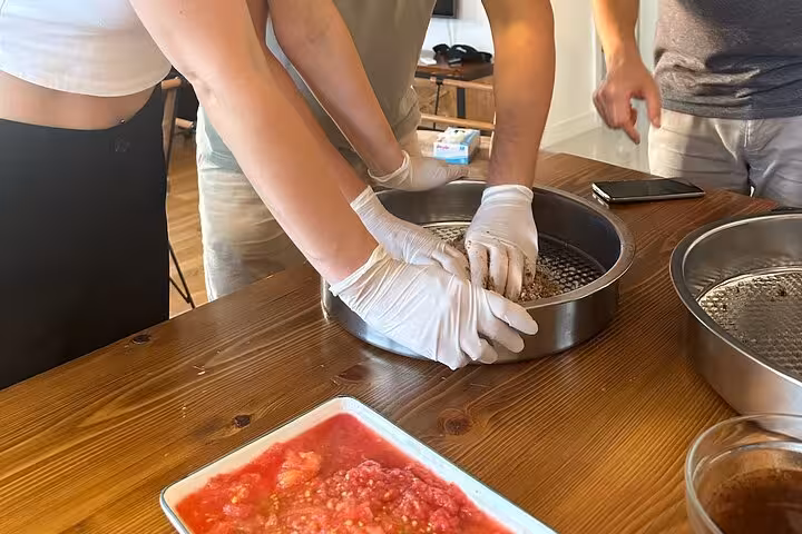Hands kneading Çiğ Köfte mixture in tray during Turkish at-home cooking class with local host experience
