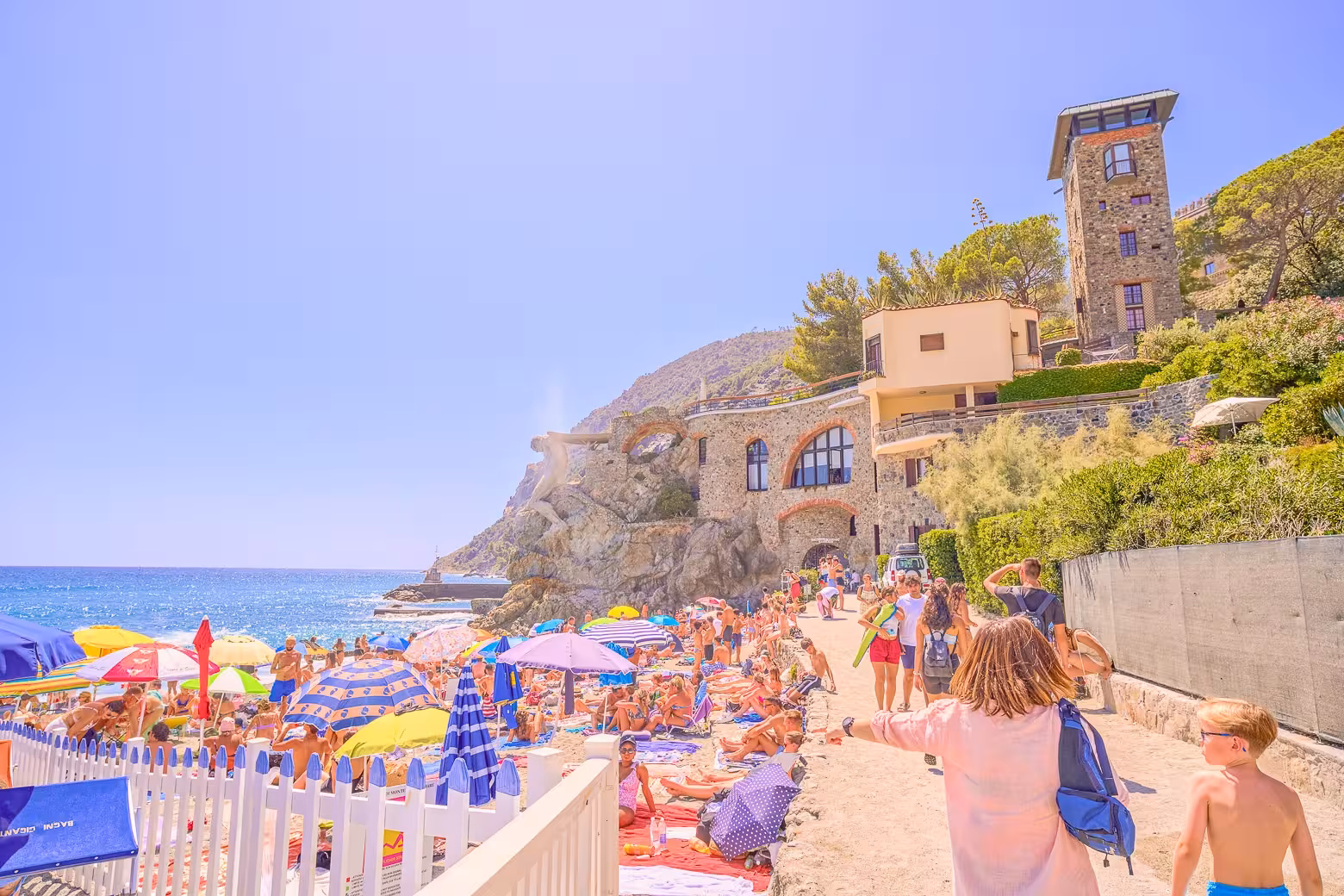 Colorful beach scene in Cinque Terre with sunbathers and historic architecture, ideal for small group tours.