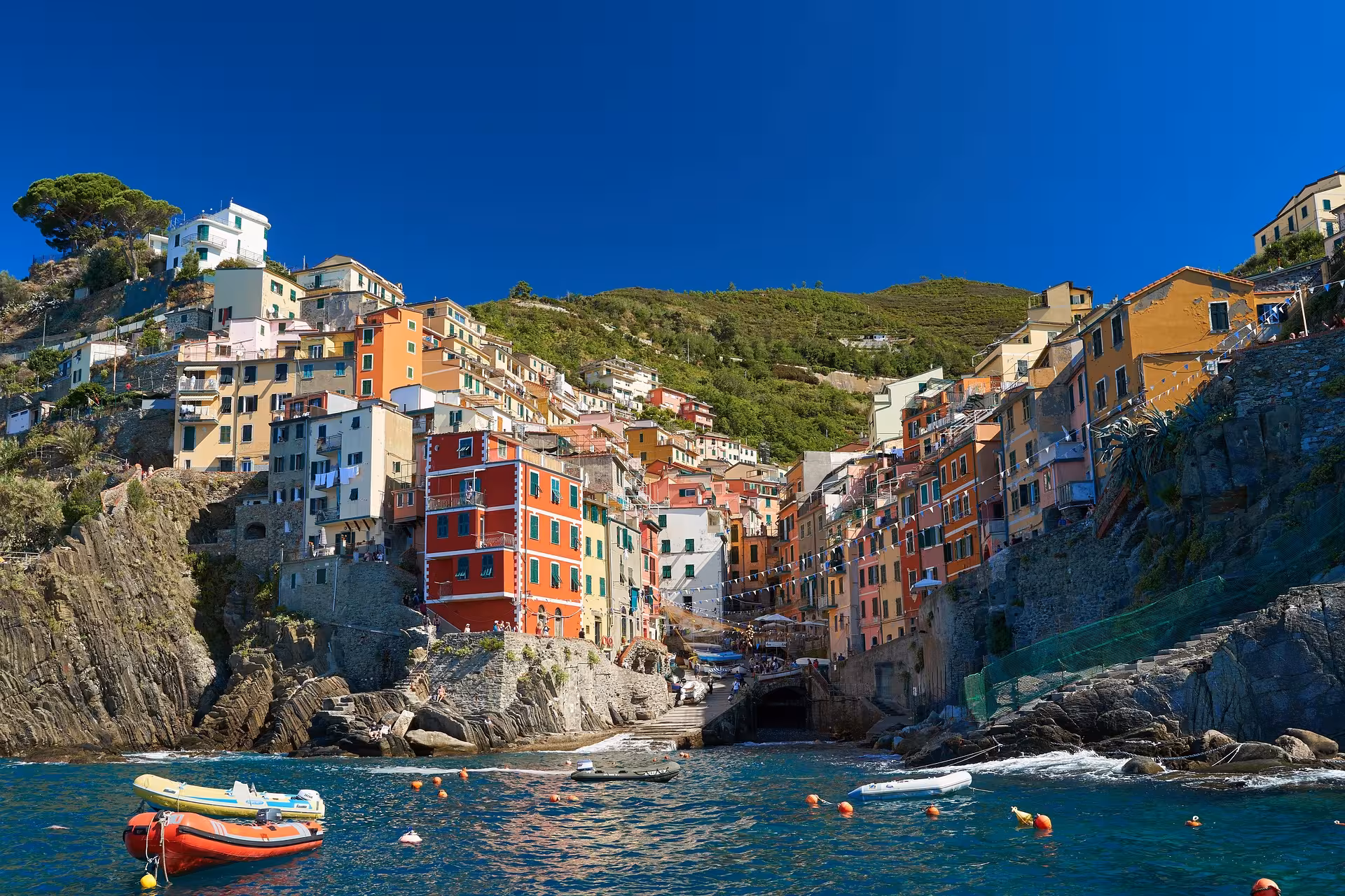 Charming hillside village in Cinque Terre featuring colorful buildings and boats in the vibrant harbor waters.