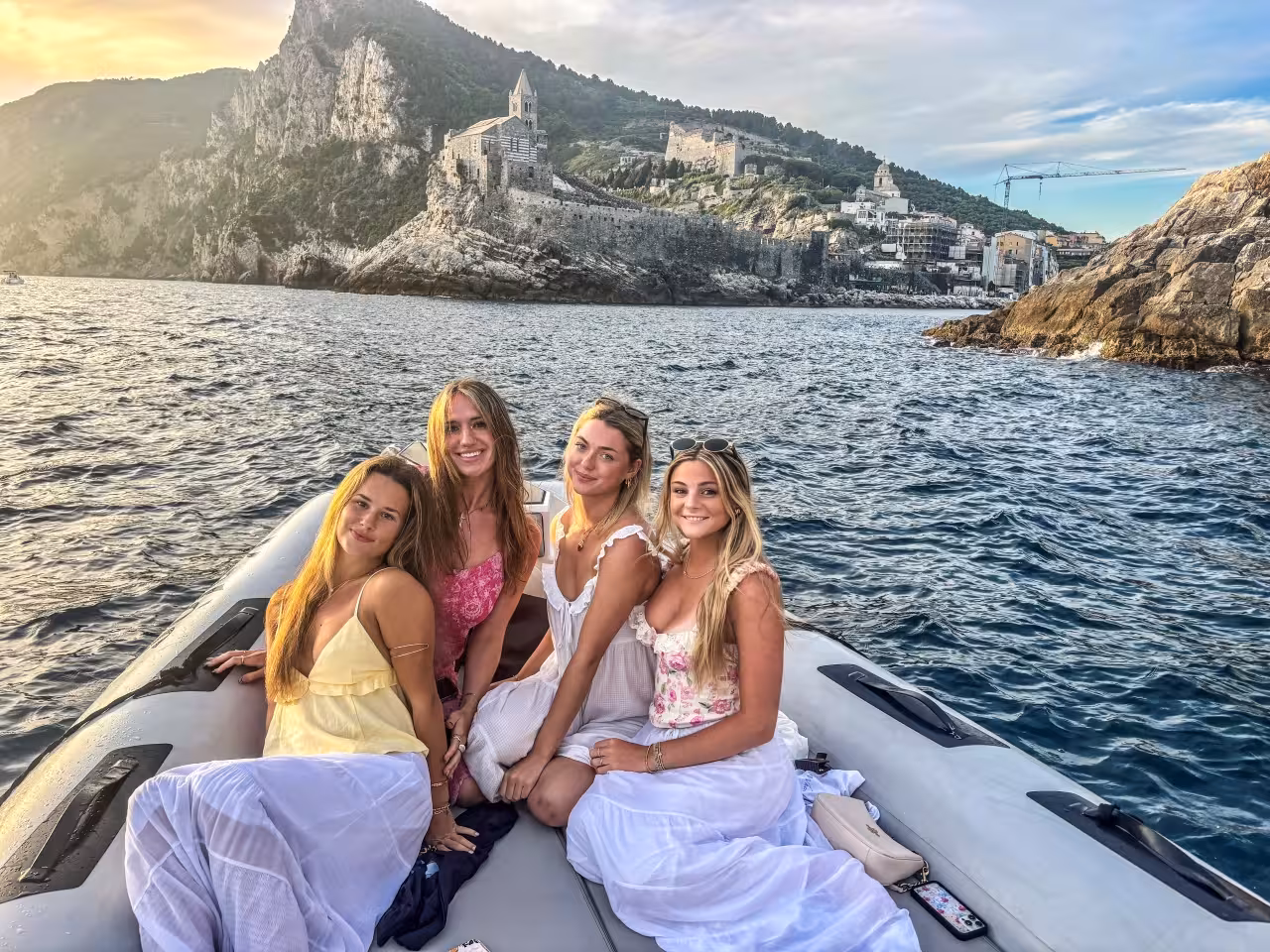 Guests on Cinque Terre full-day boat tour from La Spezia with Portovenere church and cliffs at sunset