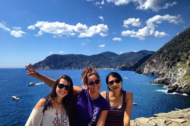 Group of friends enjoying the stunning coastal views of Cinque Terre, Italy, under a picturesque blue sky.