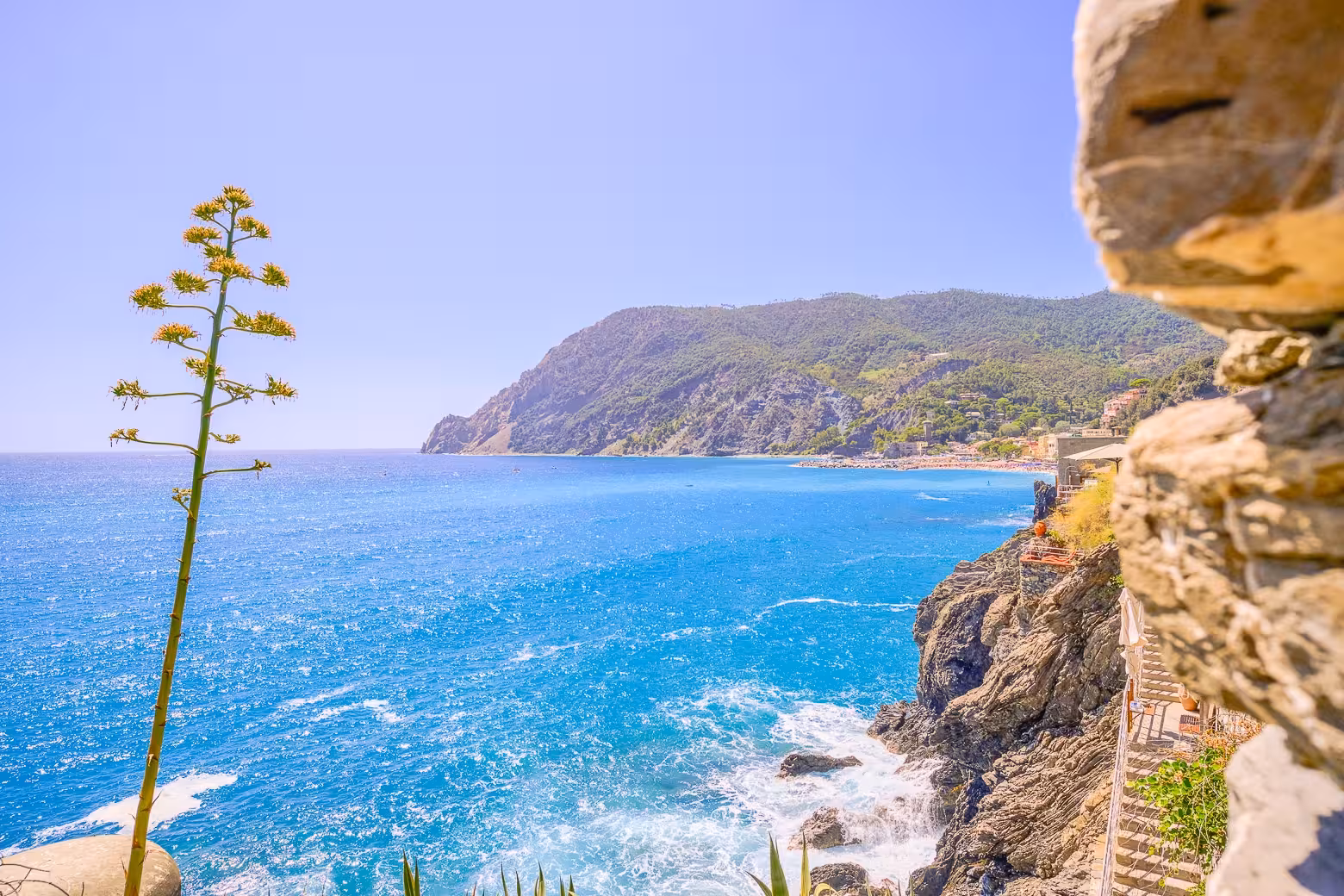 Breathtaking view of Cinque Terre's azure coastline and rugged cliffs under a clear blue sky.