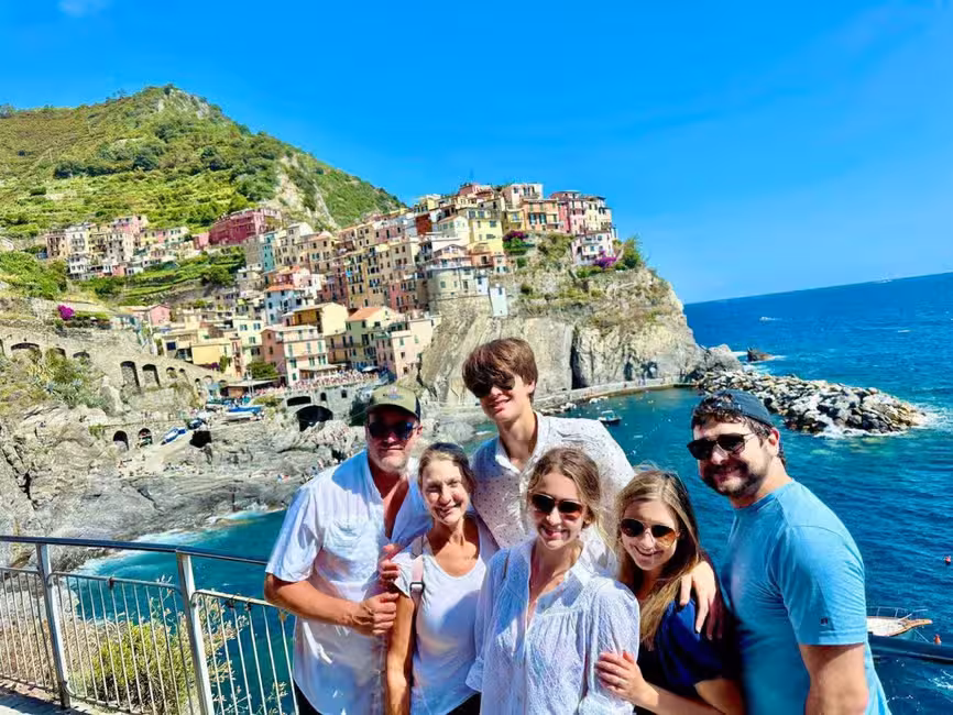 Tourists enjoying a scenic view of colorful houses perched on Cinque Terre cliffs during a private minivan tour.