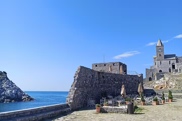 Stone terrace with café seating overlooking the Ligurian Sea and historic Portovenere church on La Spezia to Cinque Terre transfer