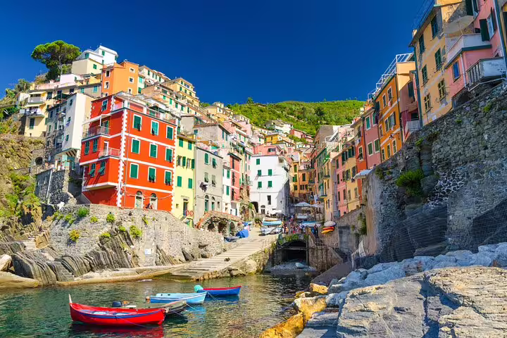 Small harbor with red and blue boats moored below vivid seaside houses in Cinque Terre on a guided Gulf of Poets tour