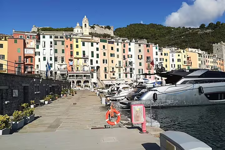 Luxury yachts moored by pastel waterfront buildings in a Cinque Terre harbor on a transfer tour from La Spezia