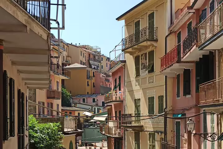 Narrow alley of pastel houses and balconies in a hilltop Cinque Terre village on a sunny day during a private walking tour