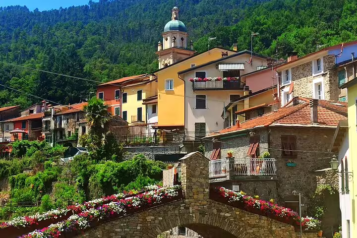 Flower-lined stone bridge and hillside village with church tower in the lush countryside near Cinque Terre on a private day trip