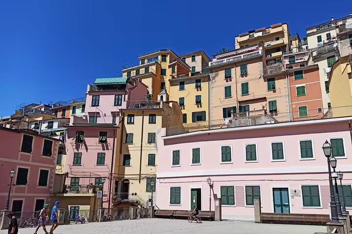 Colorful pastel houses in Riomaggiore, Cinque Terre, under a clear blue sky on a guided private day tour in Italy