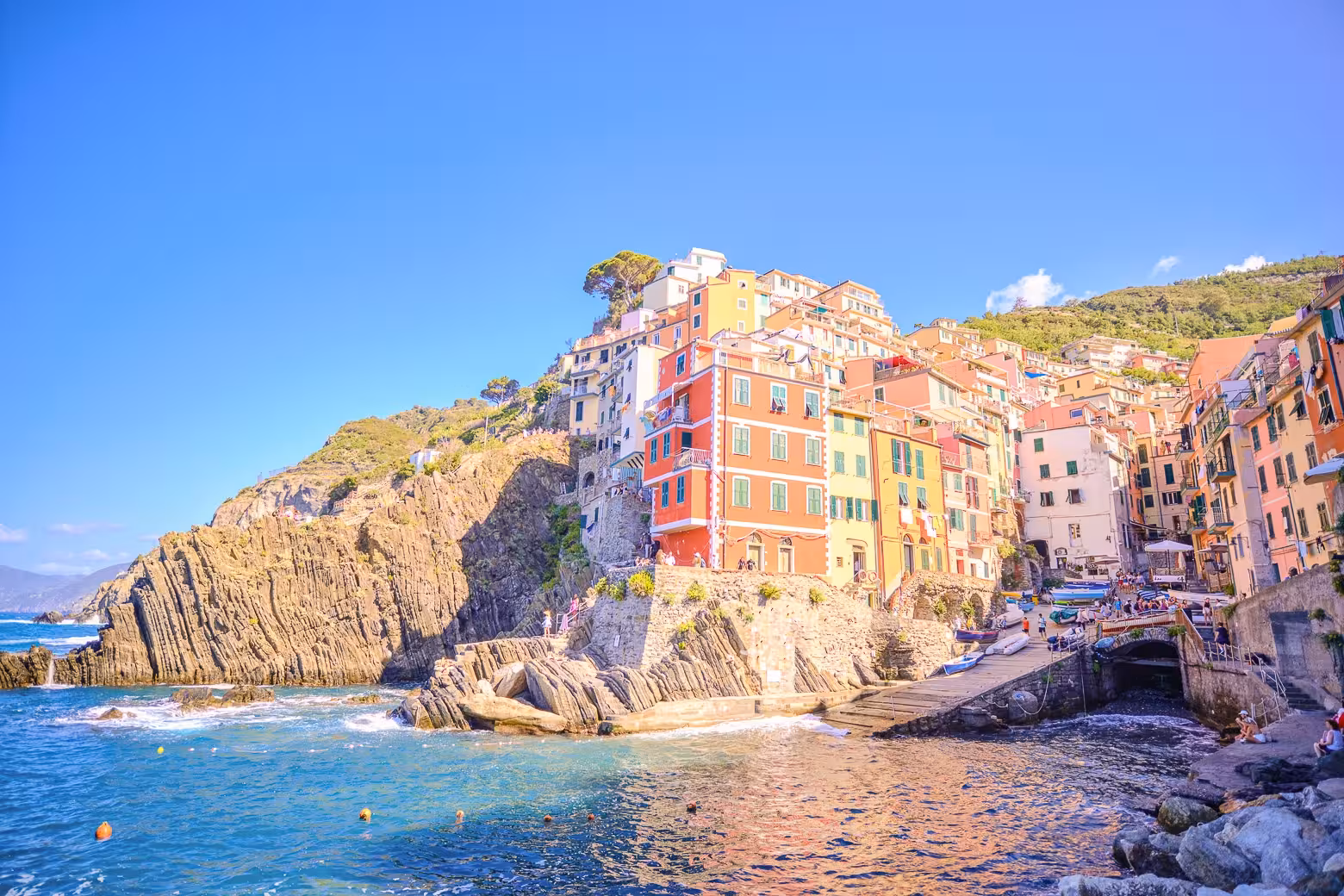 Picturesque view of Riomaggiore's colorful cliffside houses and turquoise sea in Cinque Terre, Italy.