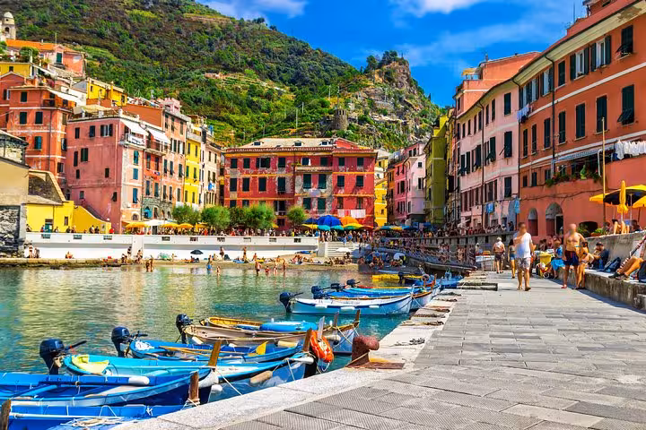 Colorful waterfront view of Vernazza harbor with vibrant boats and historic buildings on a Cinque Terre hiking tour.