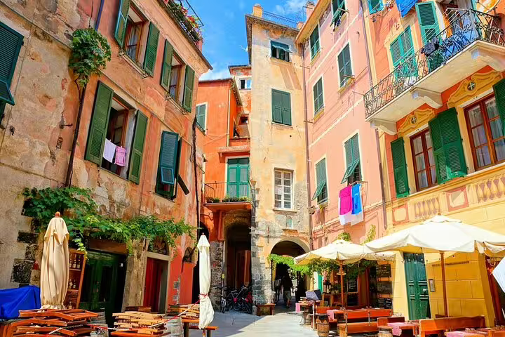 Charming narrow piazza with pastel houses, cafes and laundry lines in a Cinque Terre village on a La Spezia day trip