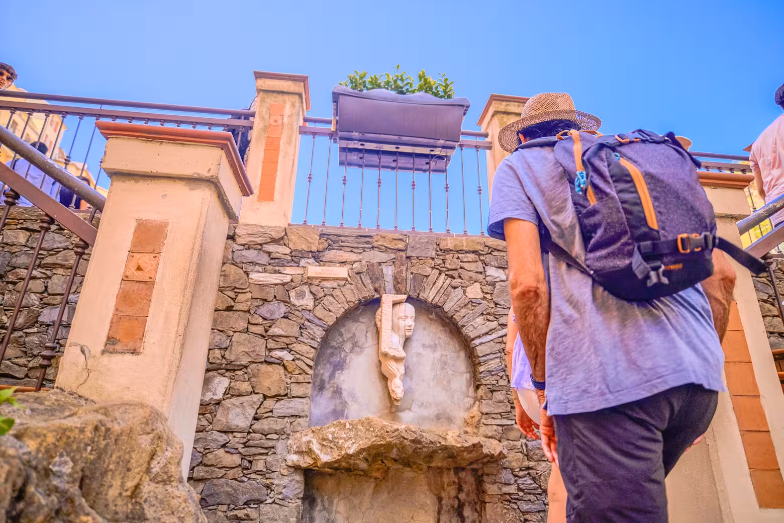 Traveler exploring a charming statue and stone wall detail in a picturesque Cinque Terre village setting.
