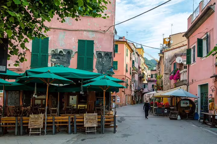 Quiet street with pastel houses and outdoor cafés in a Cinque Terre village, visited on a private one day wonderland walking tour