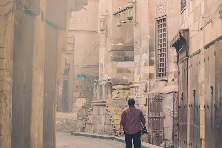 Traveler walking through Old Cairo alley near historic mosques and bazaar on Citadel and Islamic Cairo tour
