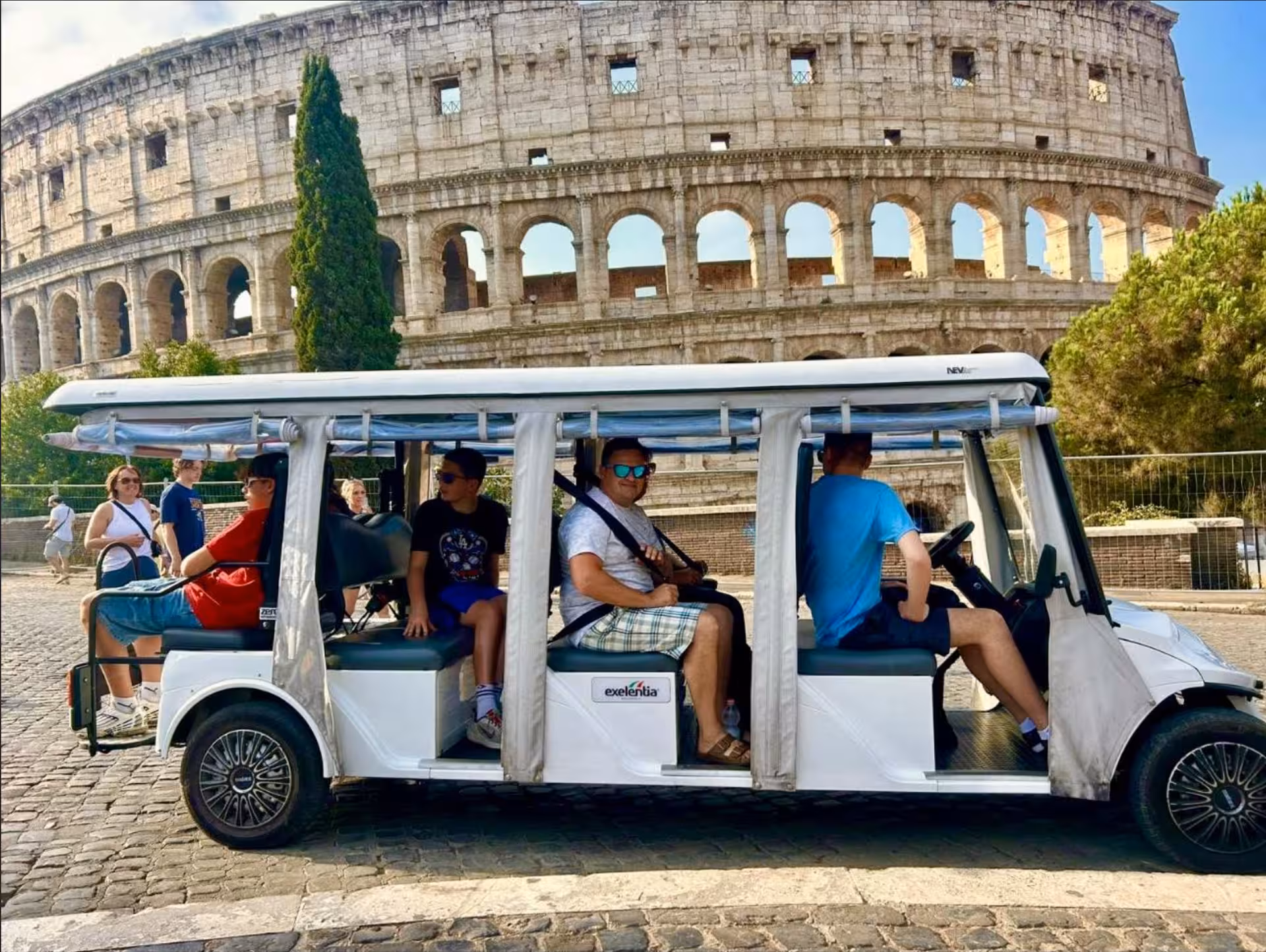 Family riding a private golf cart by the Colosseum during a Civitavecchia to Rome VIP tour and skip‑the‑line visit
