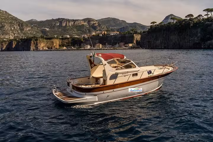 Classic Gozzo 850 boat cruising near Sorrento with scenic cliffs in the background.