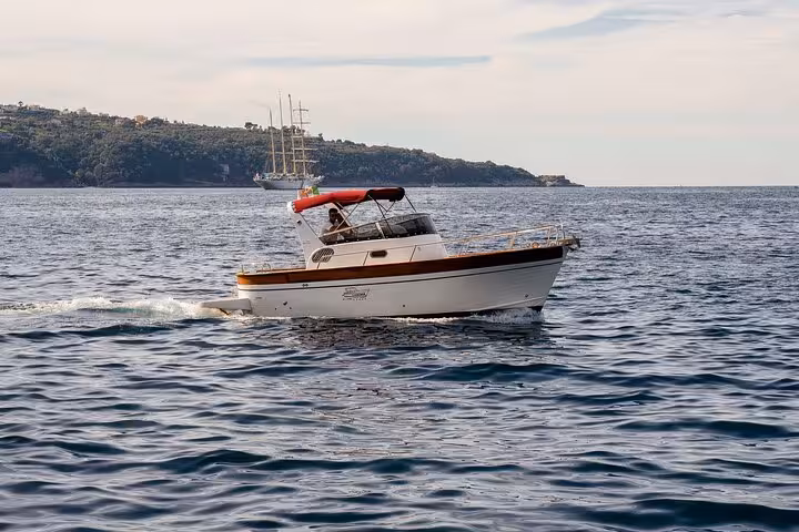 Classic Gozzo vessel navigating calm seas near Sorrento, offering private tours to Capri and Positano.